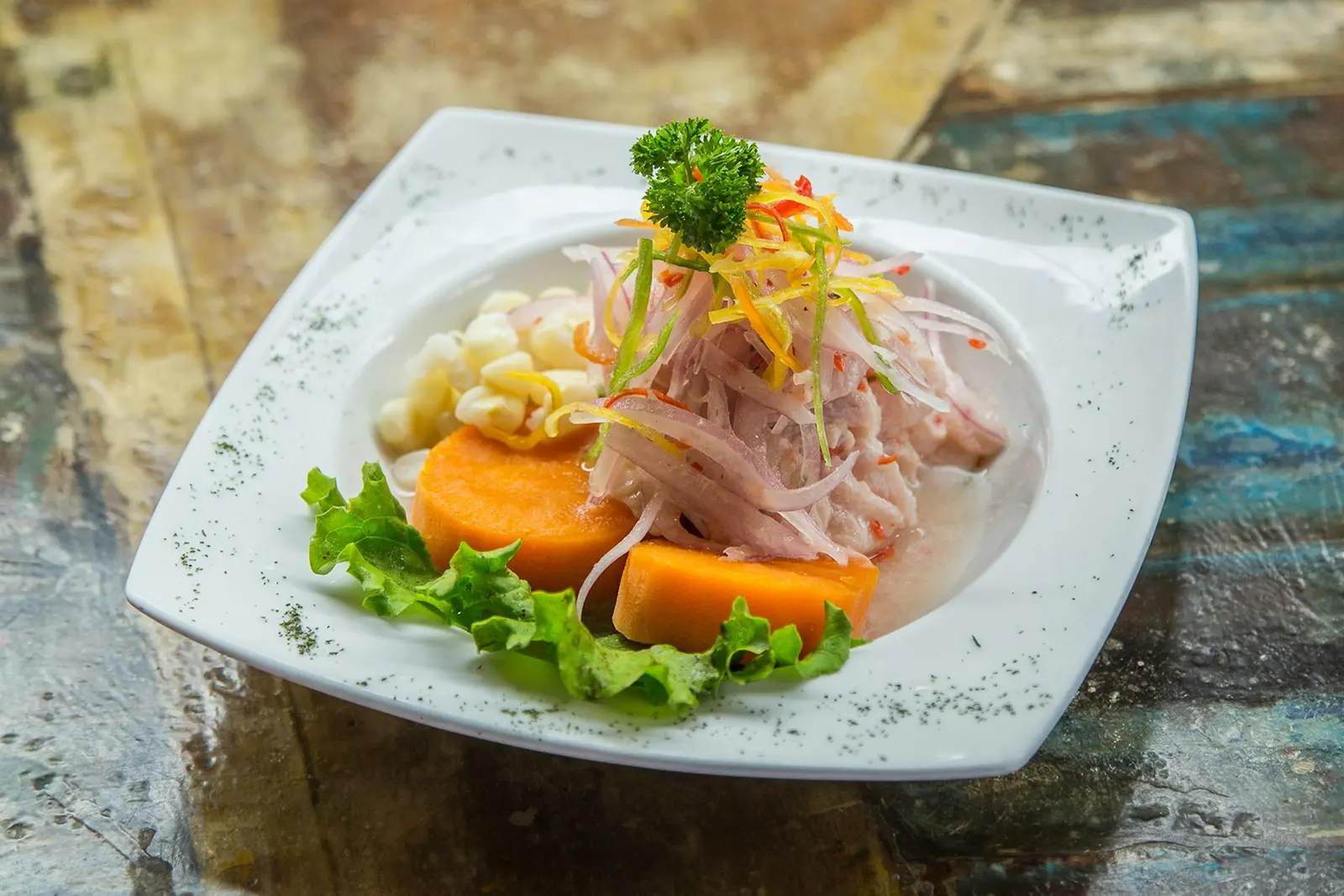Ceviche clásico de pescado con camote y choclo servido en plato