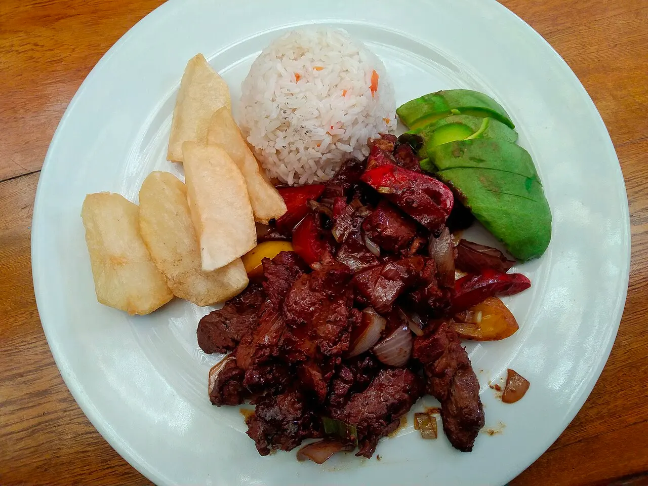 Lomo saltado con arroz blanco, papas fritas y palta, visto desde arriba
